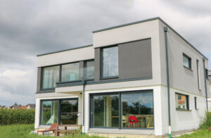 Modernes kubisches Einfamilienhaus mit weißer Fassade, anthrazitfarbenen Elementen und Flachdach, bodentiefen Fenstern und elegant zurückspringendem Obergeschoss. Gebaut vom Bauunternehmen heimART.